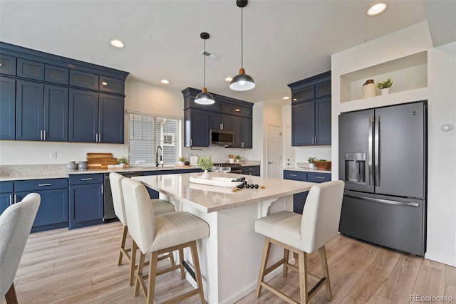 kitchen featuring appliances with stainless steel finishes, a sink, a breakfast bar, and light wood-style floors