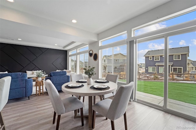 dining room featuring an accent wall, recessed lighting, and light wood-style floors