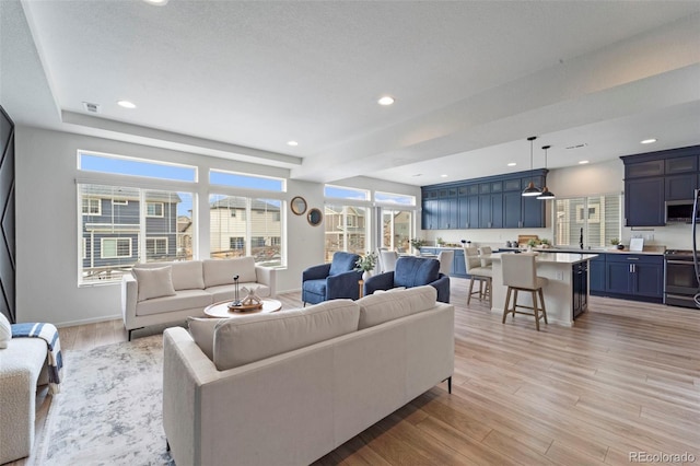 living room with light wood finished floors, visible vents, baseboards, and recessed lighting