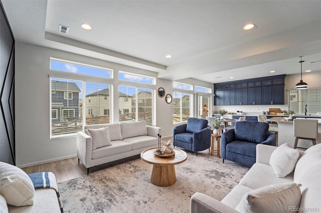 living area with recessed lighting, visible vents, light wood-style flooring, and baseboards