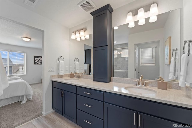 full bath with connected bathroom, visible vents, a sink, and double vanity