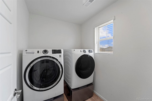 washroom featuring laundry area, wood finished floors, visible vents, baseboards, and washer and dryer