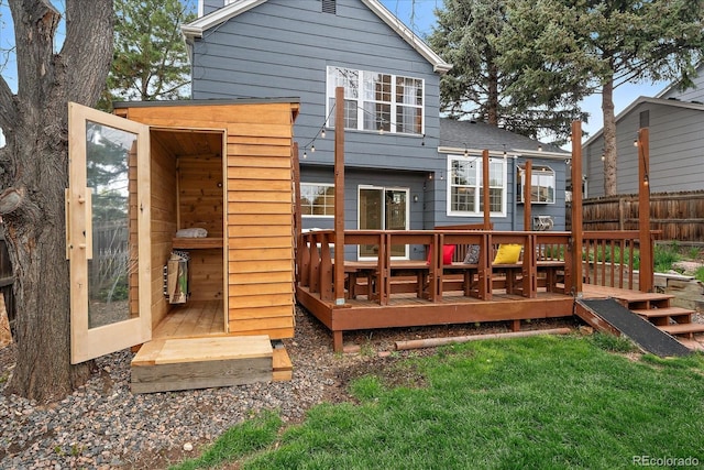 rear view of property with an outdoor structure, fence, a yard, and a wooden deck