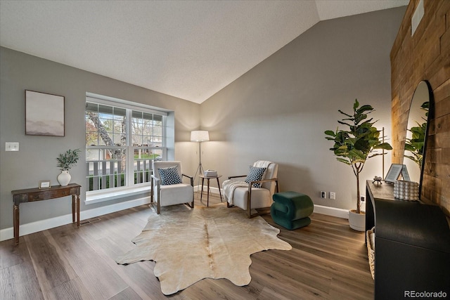 sitting room with baseboards, wood finished floors, and high vaulted ceiling