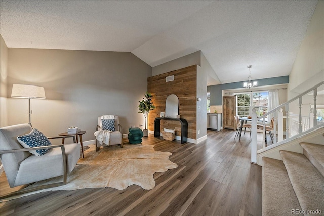 sitting room featuring vaulted ceiling, wood walls, wood finished floors, stairway, and an inviting chandelier
