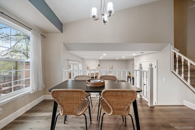 dining room with stairway, lofted ceiling, wood finished floors, and a notable chandelier