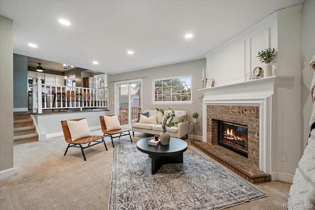 living area with baseboards, a brick fireplace, recessed lighting, and light colored carpet