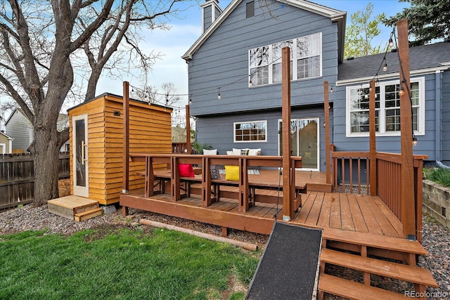 back of house with a chimney, outdoor dining area, a deck, an outbuilding, and fence