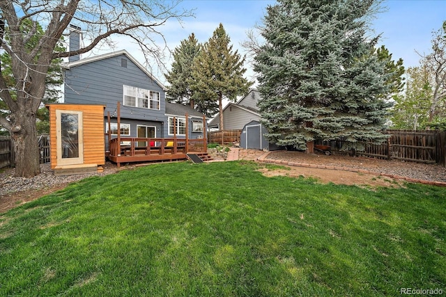 back of house featuring a chimney, a deck, an outbuilding, a fenced backyard, and a storage unit