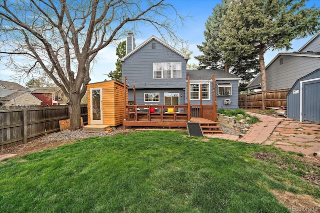 back of house with a wooden deck, a shed, a fenced backyard, an outbuilding, and a chimney