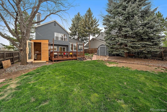 rear view of property featuring a storage shed, a deck, an outbuilding, and a fenced backyard