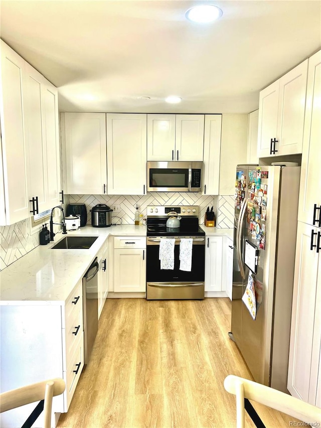 1528 Coronado Pkwy, Denver, CO 80229 - kitchen with appliances with stainless steel finishes, white cabinetry, and tasteful backsplash