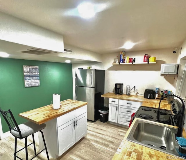 1528 Coronado Pkwy, Denver, CO 80229 - kitchen with wooden counters, freestanding refrigerator, white cabinets, light wood finished floors, and white microwave