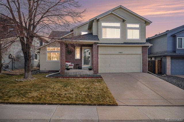 traditional-style house featuring an attached garage, brick siding, a shingled roof, driveway, and a lawn