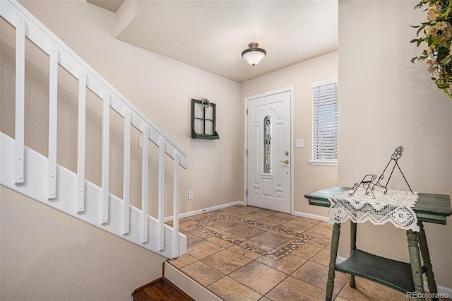 entrance foyer with stairs and baseboards