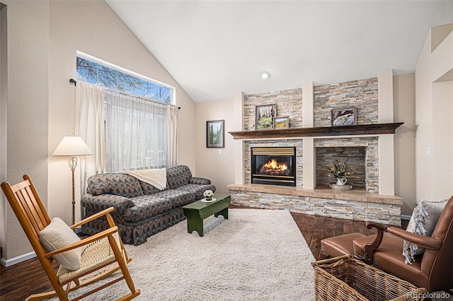 living area with lofted ceiling, wood finished floors, and a stone fireplace