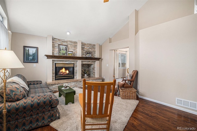 living area with baseboards, visible vents, lofted ceiling, wood finished floors, and a fireplace