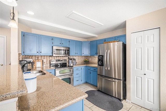 kitchen with light tile patterned floors, blue cabinets, stainless steel appliances, a sink, and backsplash