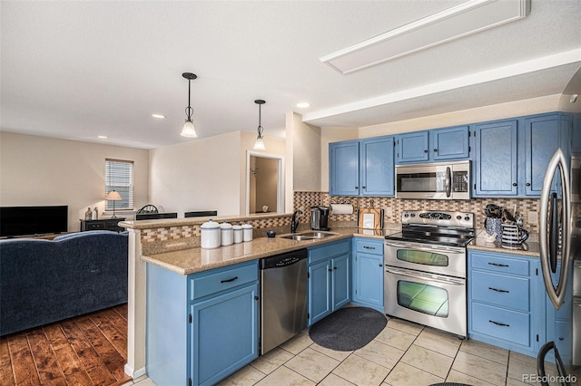 kitchen with appliances with stainless steel finishes, open floor plan, a peninsula, and blue cabinetry