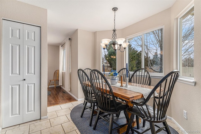 dining area featuring baseboards, light tile patterned flooring, and a notable chandelier