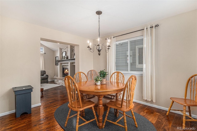 dining area with a chandelier, a glass covered fireplace, wood-type flooring, and baseboards