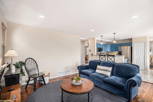 living room with recessed lighting, light wood-type flooring, visible vents, and baseboards