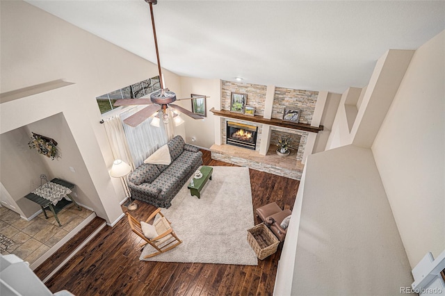 living area with a ceiling fan, lofted ceiling, a fireplace, and wood finished floors