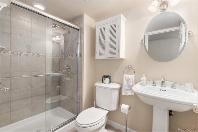 bathroom with a stall shower, baseboards, and toilet