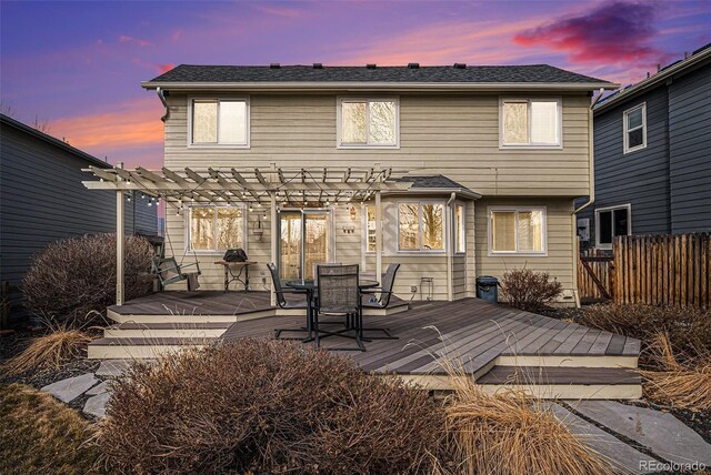 rear view of property featuring fence, a wooden deck, and a pergola