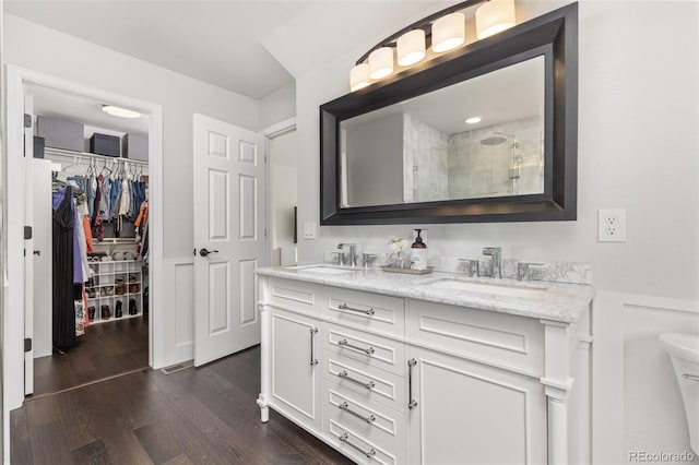 5733 S Yakima Way, Aurora, CO 80015 - full bath with double vanity, wood finished floors, tiled shower, a walk in closet, and a wainscoted wall