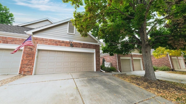 view of front of property featuring concrete driveway, brick siding, and a shingled roof