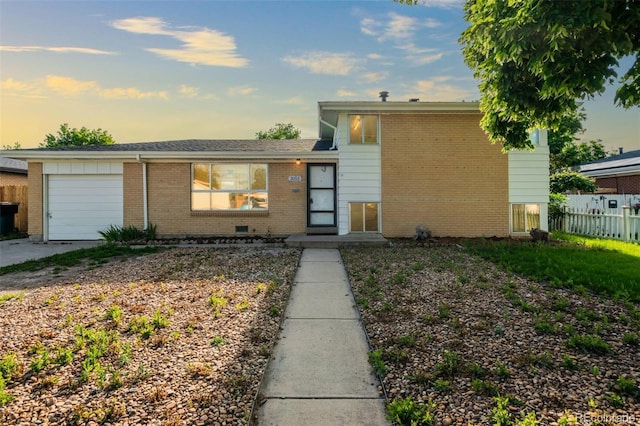 3055 Carson St, Aurora, CO 80011 - split level home featuring a garage, brick siding, and driveway