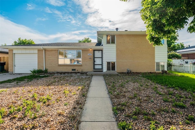 3055 Carson St, Aurora, CO 80011 - split level home featuring a garage, brick siding, and concrete driveway