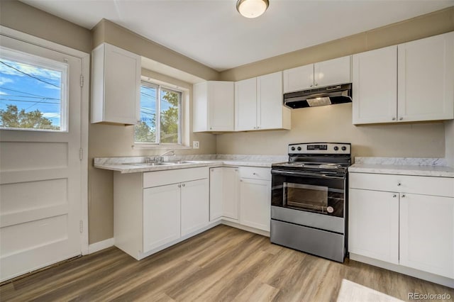 3055 Carson St, Aurora, CO 80011 - kitchen with electric stove, under cabinet range hood, light countertops, light wood-style floors, and white cabinets