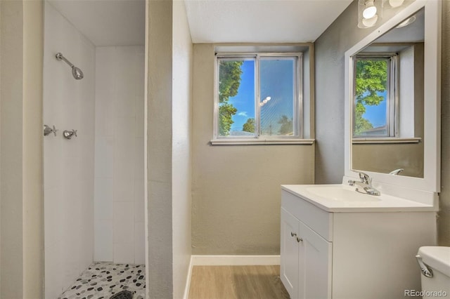 3055 Carson St, Aurora, CO 80011 - bathroom featuring vanity, tiled shower, toilet, baseboards, and wood finished floors