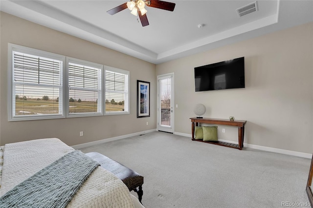 carpeted bedroom with ceiling fan, a raised ceiling, and access to outside