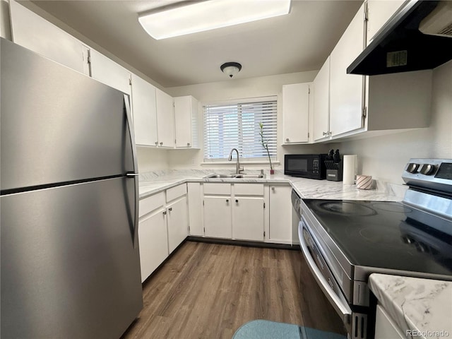 kitchen featuring white cabinets, dark wood finished floors, appliances with stainless steel finishes, under cabinet range hood, and a sink