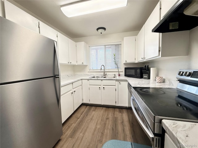 kitchen featuring white cabinets, appliances with stainless steel finishes, under cabinet range hood, a sink, and dark wood-style floors