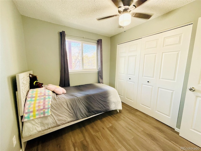 bedroom featuring a closet, a ceiling fan, wood finished floors, and a textured ceiling