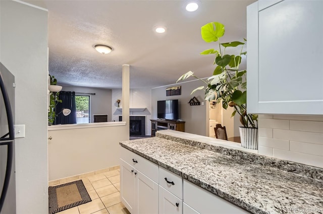2280 S Oswego Way Unit 104, Aurora, CO 80014 - kitchen with white cabinets, backsplash, recessed lighting, light stone countertops, and light tile patterned floors