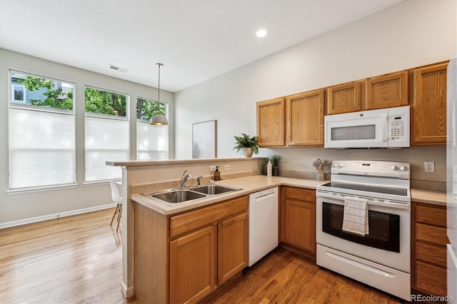 2870 W Riverwalk Cir Unit B, Littleton, CO 80123 - kitchen featuring white appliances, a peninsula, light countertops, light wood-type flooring, and brown cabinets
