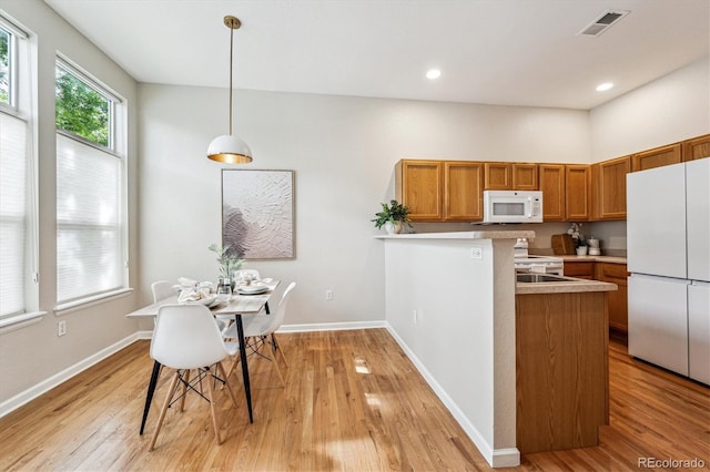 2870 W Riverwalk Cir Unit B, Littleton, CO 80123 - kitchen featuring white appliances, brown cabinets, light wood-style floors, light countertops, and hanging light fixtures