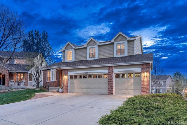 traditional-style house with a garage, concrete driveway, and brick siding
