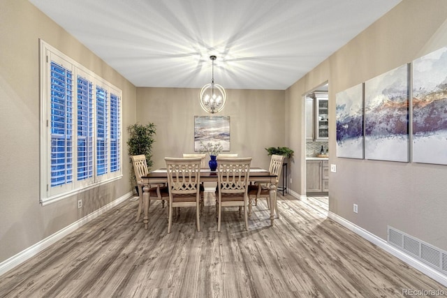 dining room featuring baseboards, a chandelier, wood finished floors, and visible vents