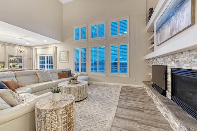 living area with baseboards, a high ceiling, wood finished floors, and a fireplace