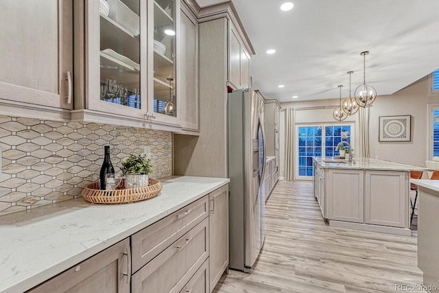 kitchen featuring stainless steel fridge, a sink, light wood-style floors, and light stone countertops
