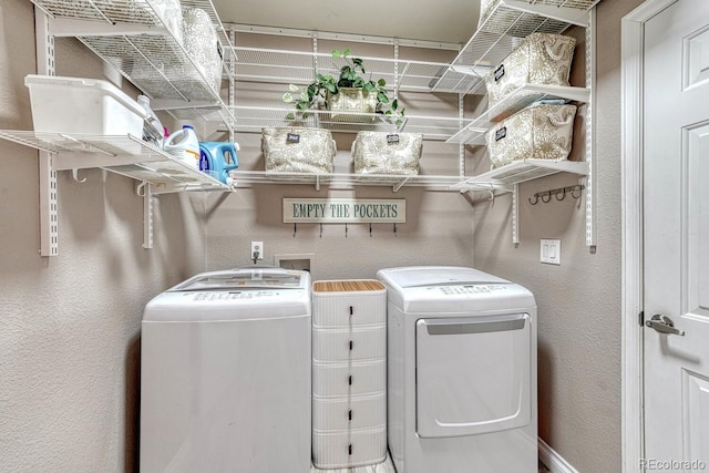 laundry area featuring independent washer and dryer, laundry area, and a textured wall