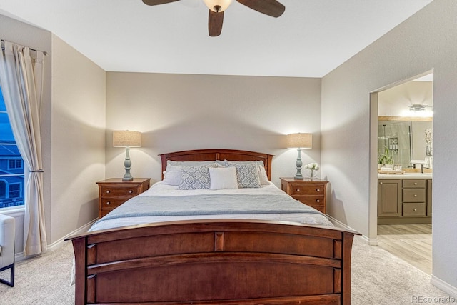 bedroom with baseboards, light carpet, a ceiling fan, and connected bathroom