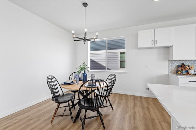 dining space with light wood-type flooring, a chandelier, and baseboards