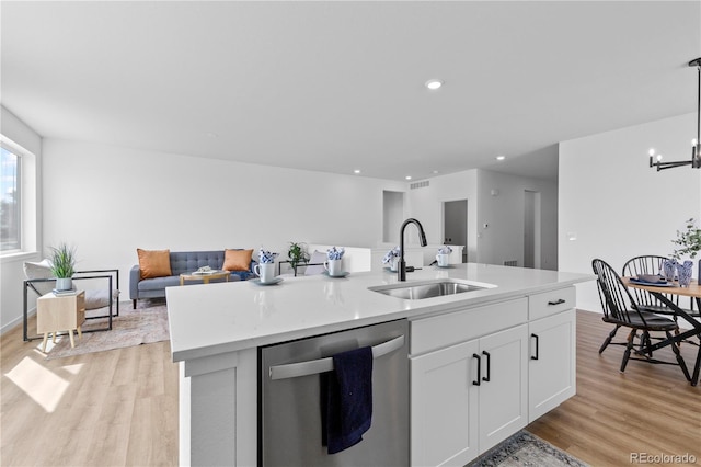 kitchen featuring dishwasher, a sink, open floor plan, light wood-style flooring, and white cabinets